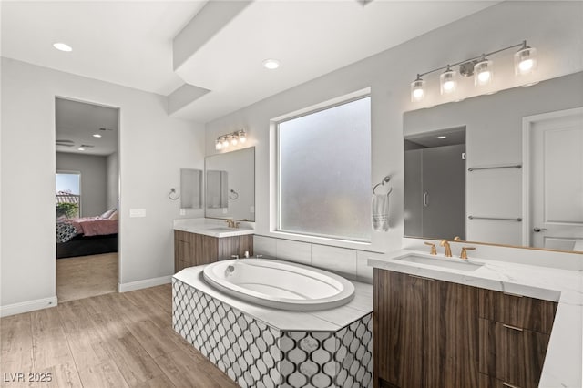 bathroom with hardwood / wood-style flooring, vanity, and a relaxing tiled tub