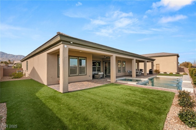 back of house featuring ceiling fan, a yard, a patio, a pool with hot tub, and a mountain view