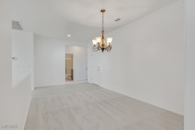 carpeted spare room featuring an inviting chandelier