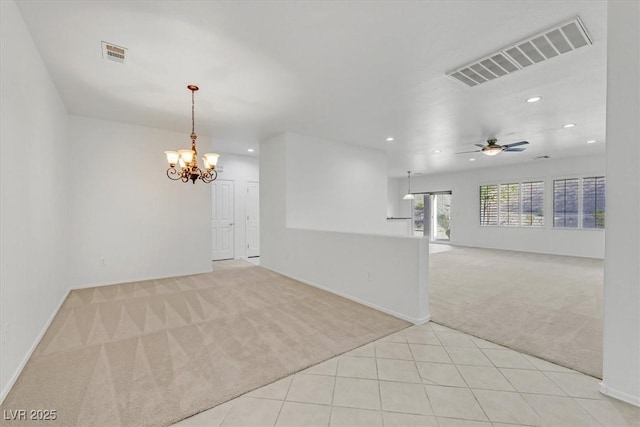 spare room featuring ceiling fan with notable chandelier and light carpet