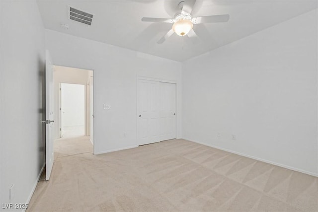 unfurnished bedroom with light colored carpet, a closet, and ceiling fan