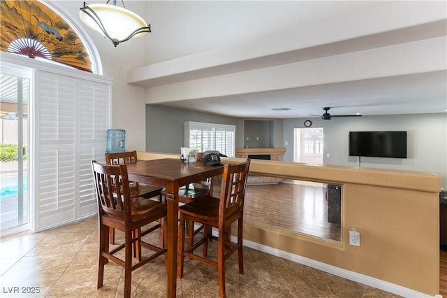 dining room with light tile patterned floors, ceiling fan, a fireplace, and baseboards