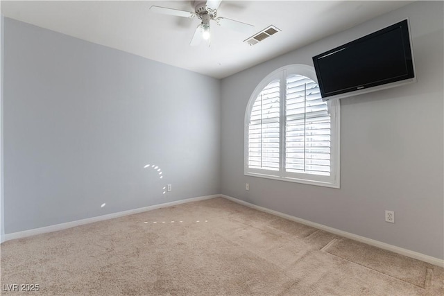 carpeted empty room with visible vents, baseboards, and a ceiling fan