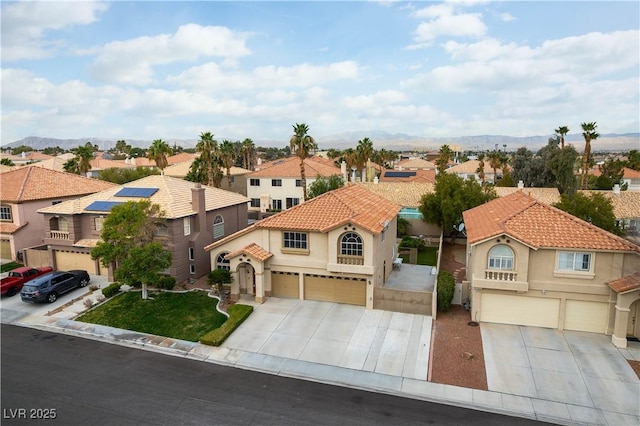 mediterranean / spanish-style home featuring a garage, a residential view, concrete driveway, and stucco siding