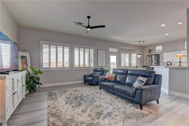 living room featuring ceiling fan, light hardwood / wood-style flooring, and a healthy amount of sunlight