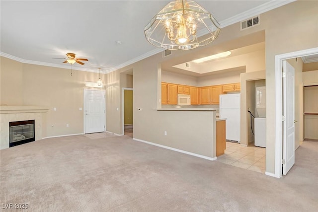 unfurnished living room with ornamental molding, ceiling fan with notable chandelier, light colored carpet, and a high end fireplace