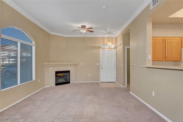 unfurnished living room with a tile fireplace, ornamental molding, light colored carpet, and ceiling fan