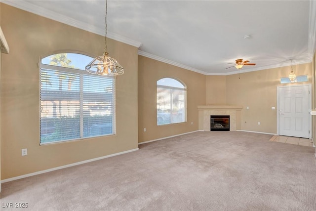 unfurnished living room featuring light carpet, a tiled fireplace, ornamental molding, and ceiling fan