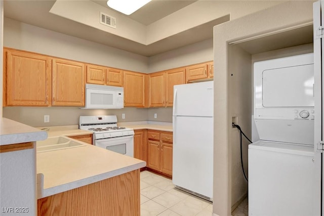 kitchen with stacked washing maching and dryer, sink, light brown cabinets, and white appliances