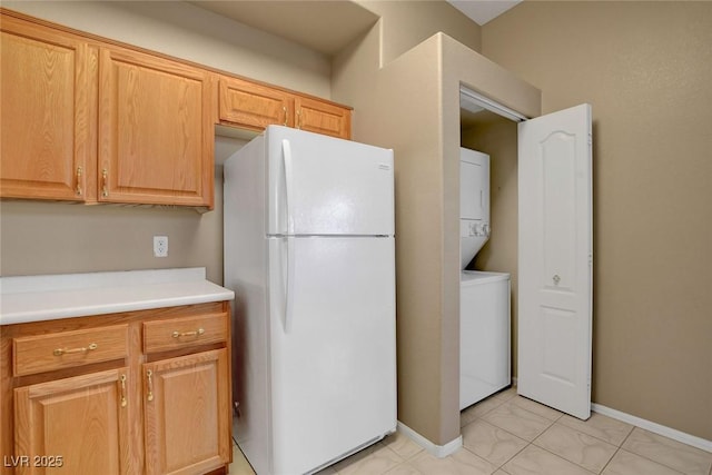 kitchen with stacked washer and clothes dryer and white fridge