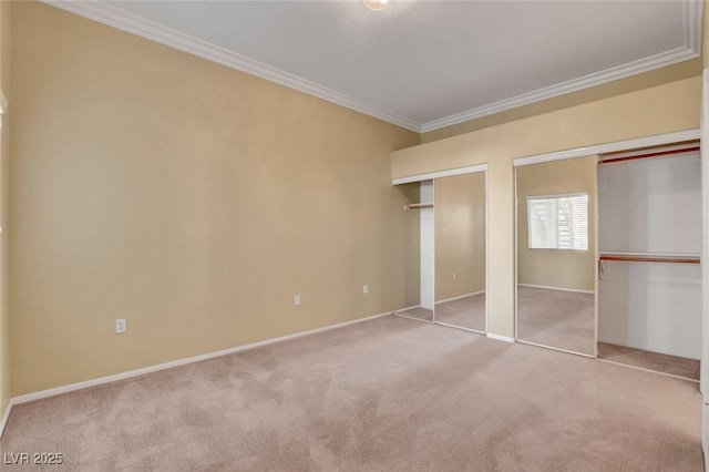 unfurnished bedroom with crown molding, light colored carpet, and multiple closets