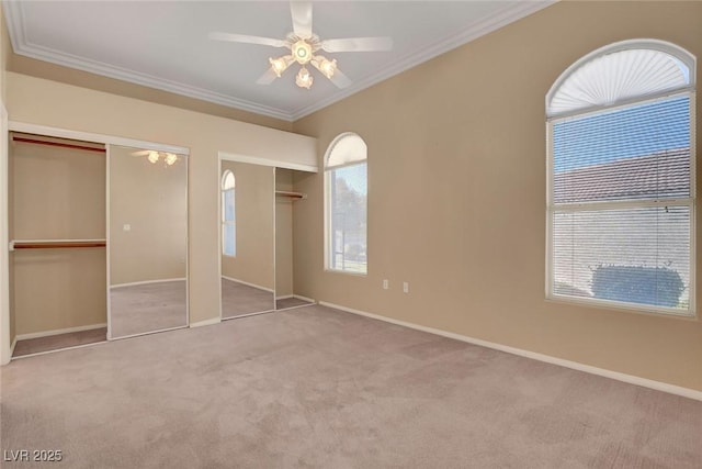 unfurnished bedroom with multiple closets, crown molding, light carpet, and ceiling fan