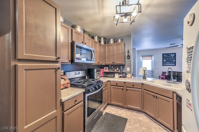 kitchen featuring appliances with stainless steel finishes, sink, a textured ceiling, and kitchen peninsula