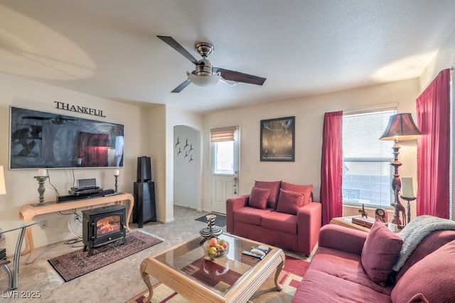 living room with a wood stove and ceiling fan