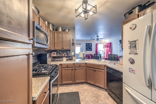 kitchen featuring sink, ceiling fan, stainless steel appliances, light stone counters, and kitchen peninsula