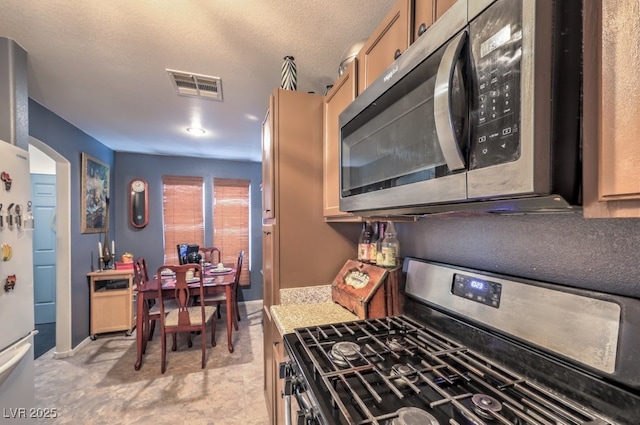 kitchen featuring light stone countertops, a textured ceiling, and appliances with stainless steel finishes