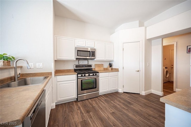 kitchen with appliances with stainless steel finishes, washer / clothes dryer, sink, and white cabinets