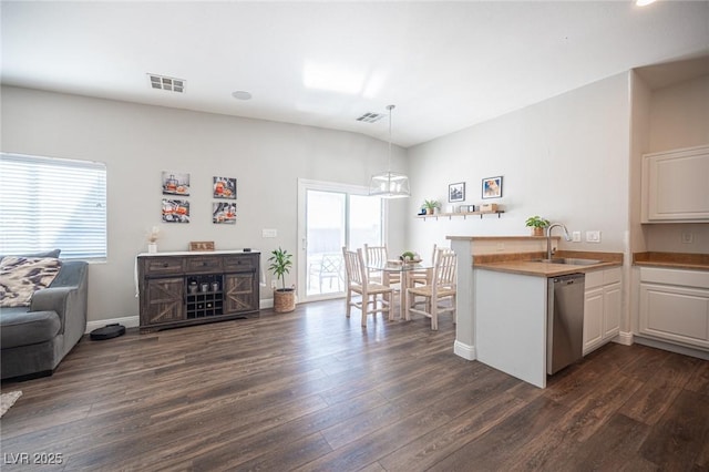 kitchen with decorative light fixtures, sink, white cabinets, stainless steel dishwasher, and kitchen peninsula