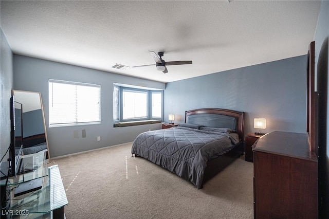 bedroom with ceiling fan, light colored carpet, and a textured ceiling