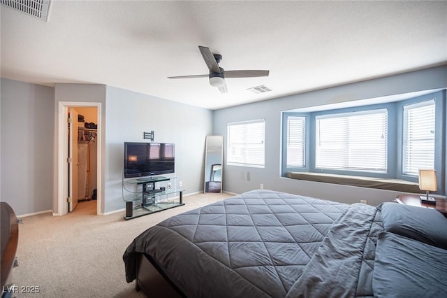 bedroom featuring multiple windows, a spacious closet, light carpet, and ceiling fan