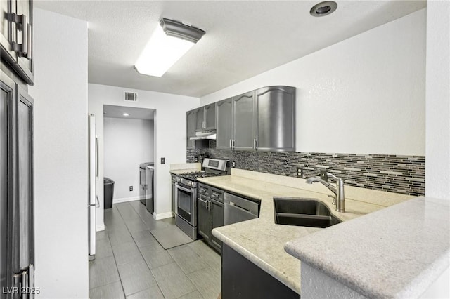 kitchen with sink, tasteful backsplash, kitchen peninsula, stainless steel appliances, and washing machine and dryer