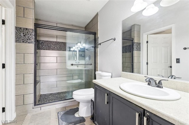 bathroom featuring vanity, a shower with door, and toilet