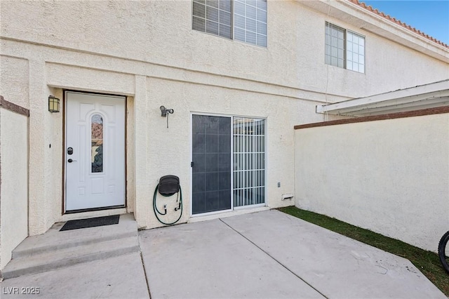 view of exterior entry with a patio area