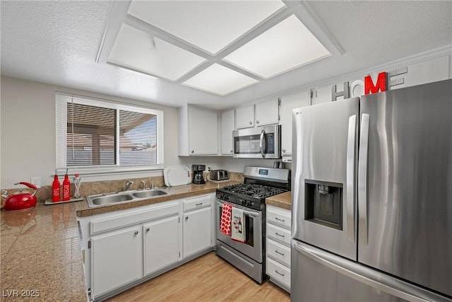 kitchen featuring sink, light wood-type flooring, appliances with stainless steel finishes, kitchen peninsula, and white cabinets