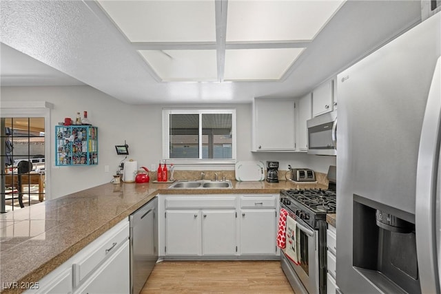 kitchen with appliances with stainless steel finishes, sink, light hardwood / wood-style flooring, and white cabinets