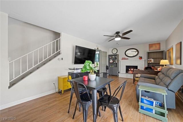 dining space with light hardwood / wood-style flooring, a fireplace, and ceiling fan