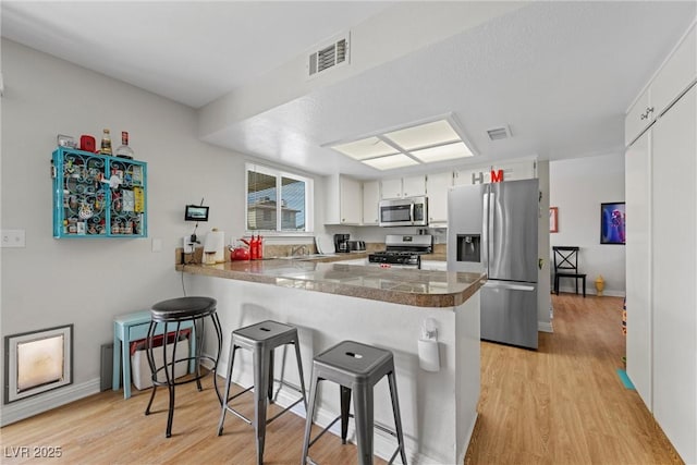 kitchen with sink, stainless steel appliances, kitchen peninsula, and white cabinets