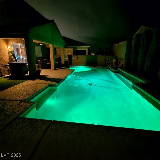 pool at night with a patio area