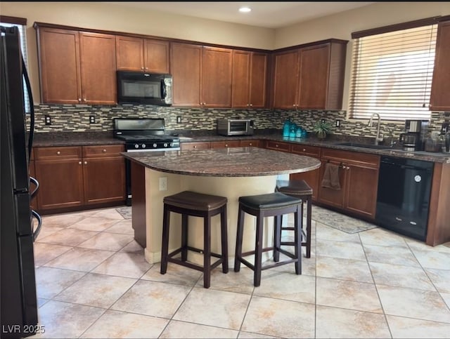 kitchen featuring sink, a center island, tasteful backsplash, black appliances, and dark stone counters