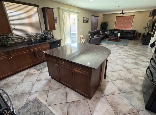 kitchen featuring a kitchen island, dishwasher, sink, dark stone countertops, and decorative backsplash