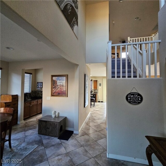 hall with a high ceiling and light tile patterned floors