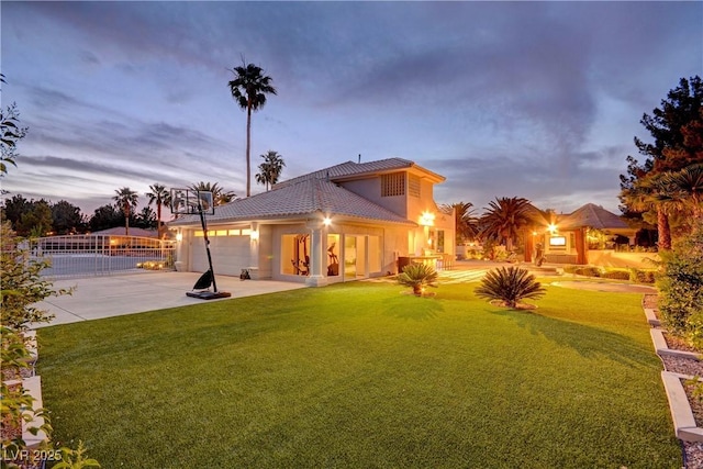 back house at dusk with a yard and a garage