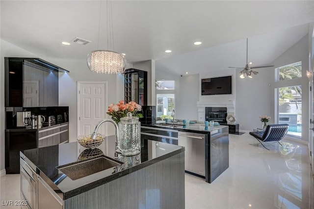 kitchen featuring sink, hanging light fixtures, dishwasher, and a center island with sink