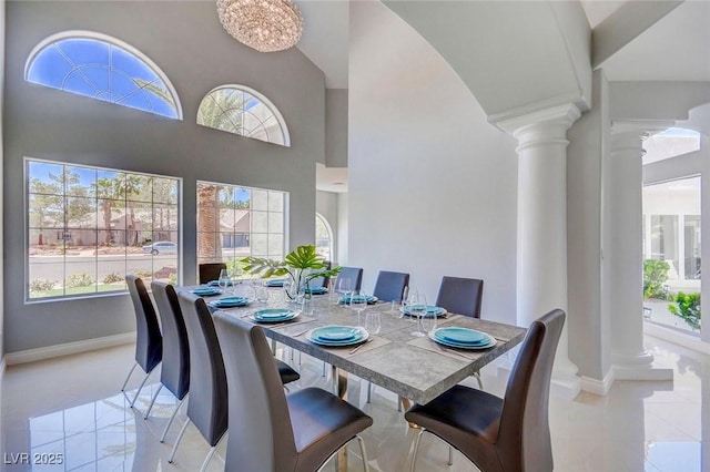 dining area with a towering ceiling, light tile patterned floors, and ornate columns