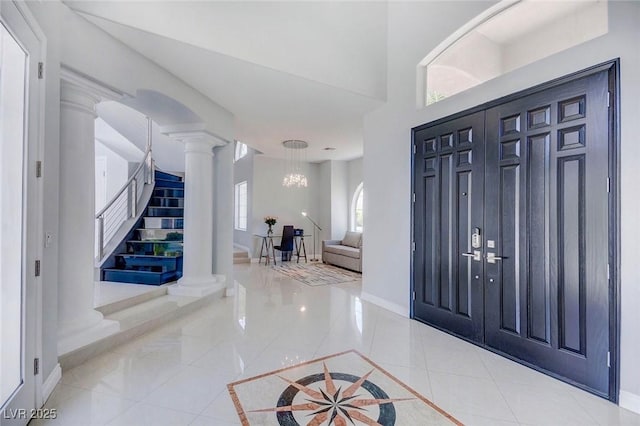 foyer entrance featuring an inviting chandelier, light tile patterned flooring, and ornate columns