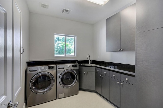 clothes washing area featuring sink, cabinets, and washer and dryer