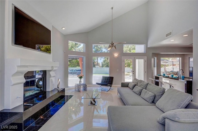 living room with french doors, a high end fireplace, sink, and high vaulted ceiling