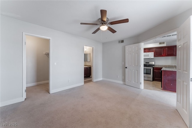 unfurnished living room with sink, light carpet, and ceiling fan