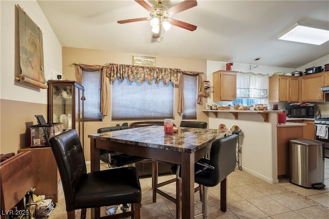 tiled dining room with ceiling fan and a skylight