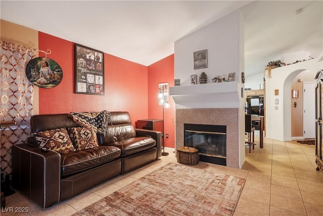 living room featuring vaulted ceiling, a tile fireplace, and light tile patterned floors