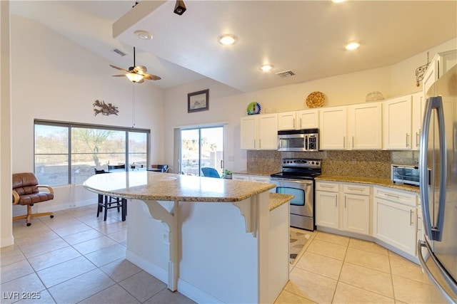 kitchen with a kitchen island, white cabinetry, appliances with stainless steel finishes, and light stone counters