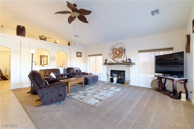 carpeted living room with a tiled fireplace, lofted ceiling, and ceiling fan