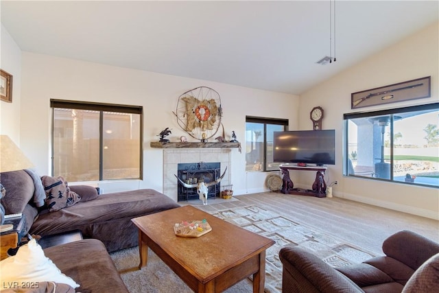 carpeted living room with a tiled fireplace, plenty of natural light, and lofted ceiling