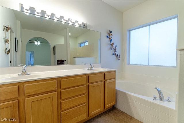 bathroom with ceiling fan, vanity, and tiled bath