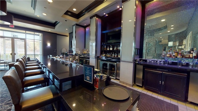 bar featuring crown molding, light tile patterned floors, beverage cooler, and a tray ceiling