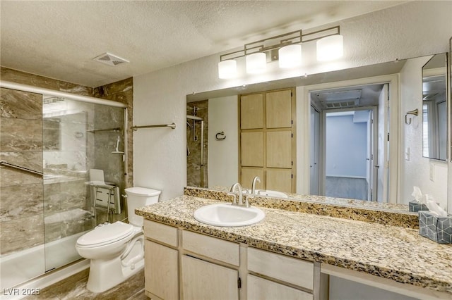 bathroom featuring vanity, toilet, a shower with door, and a textured ceiling